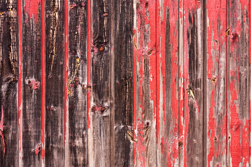 An old worn barn or wooden fence with chipped red paint.